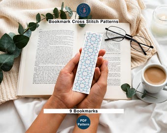 Może przedstawiać: Zakładka ze wzorem geometrycznym w kolorze niebieskim i białym jest trzymana nad otwartą książką. Widoczny jest tekst "Bookmark Cross Stitch Patterns" i "9 Bookmarks". Na zdjęciu znajduje się również filiżanka kawy, okulary i świeca.