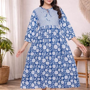 Könnte beinhalten: Blau-weißes Kleid mit Blumenmuster und Dreiviertelärmeln. Das Kleid hat einen runden Ausschnitt mit Schlüssellochdetail und einen fließenden Rock. Das Kleid ist knielang und für Freizeitkleidung geeignet.