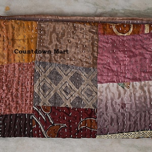 Könnte beinhalten: Ein Patchwork-Textil mit warmen Farben wie Orange, Braun und Burgunderrot. Das Textil besteht aus Stoffquadraten, die mit weißem Faden zusammengenäht sind. Der Text "Countdown Mart" ist sichtbar.