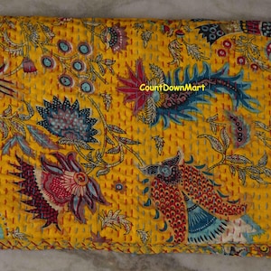Peut inclure: Textile jaune pli&eacute; avec un motif floral dans les tons de bleu, rouge et blanc. Le textile a un aspect matelass&eacute; avec des coutures visibles. Le texte "CountDownMart" est visible sur le textile.