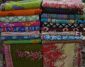 May include: A stack of colorful kantha quilts with various floral and geometric patterns. The quilts are made of recycled saris and are hand-stitched. The quilts are arranged in two stacks, one on the left and one on the right. The quilts are all different sizes and shapes. The quilts are all made of cotton and are very soft. The quilts are perfect for adding a touch of color and style to any room.
