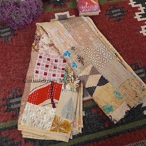 May include: A folded, patchwork textile with a variety of patterns and colors, including beige, red, and brown. The textile has visible stitching and a mix of geometric and floral designs. The text "Countdown Mart" is visible on the textile.