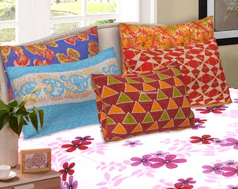 May include: Four patterned pillowcases in various colors and designs, including red, orange, blue, and green, arranged on a white bedspread with a pink floral pattern.