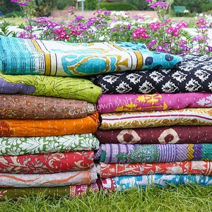 May include: A stack of colorful kantha quilts with various patterns and designs. The quilts are made of cotton and are hand-stitched. They are perfect for adding a touch of bohemian style to any room.