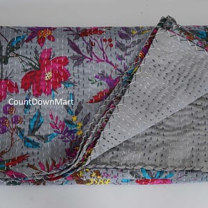 May include: Gray floral quilt with a vibrant pattern of pink, red, and blue flowers and leaves. The quilt is folded, revealing a gray interior with white stitching. The text "CountDownMart" is visible on the quilt.