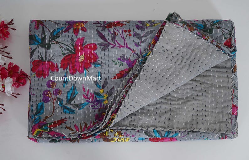 May include: Gray floral quilt with a vibrant pattern of pink, red, and blue flowers and leaves. The quilt is folded, revealing a gray interior with white stitching. The text "CountDownMart" is visible on the quilt.