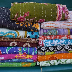 Puede incluir: Una pila de colchas kantha de colores con varios patrones florales y geométricos. Las colchas están hechas de saris reciclados y están cosidas a mano.