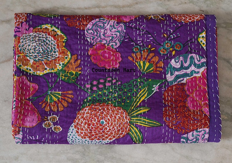 May include: A rectangular, quilted textile with a vibrant floral pattern. The design features large flowers in shades of orange, pink, and green against a deep purple background. The text "Countdown Mart" is visible. White stitching outlines the floral elements.