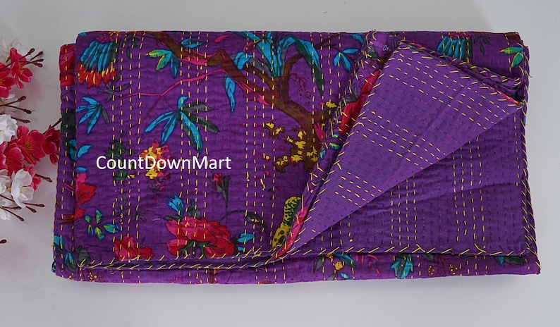May include: A folded purple quilt with a floral pattern in red, teal, and yellow. The quilt is stitched with gold thread and has a solid purple reverse side. The text "CountDownMart" is visible on the quilt.