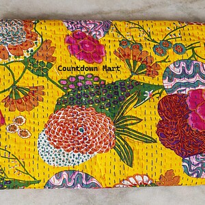May include: A yellow textile with a vibrant floral pattern. The design features large flowers in shades of pink, orange, and green, with intricate detailing. The text "Countdown Mart" is visible. The textile is likely a decorative item.