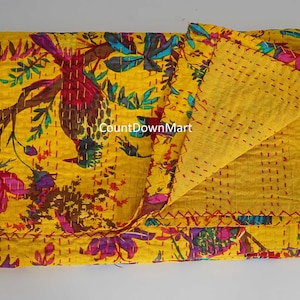 May include: A folded yellow quilt with a floral and bird pattern. The quilt features a vibrant design with red, purple, and blue accents. The text "CountDownMart" is visible on the quilt.