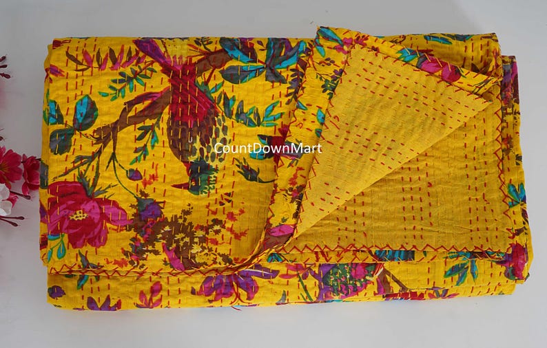 May include: A folded yellow quilt with a floral and bird pattern. The quilt features a vibrant design with red, purple, and blue accents. The text "CountDownMart" is visible on the quilt.