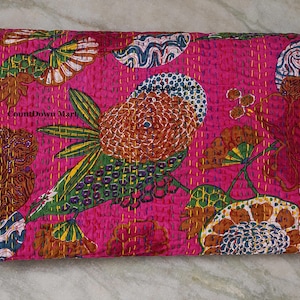May include: A folded, hot pink quilt with a large, colorful floral design. The design includes a large, stylized flower with brown, green, and white details. The quilt is stitched with yellow thread, and the text "CountDown Mart" is visible.