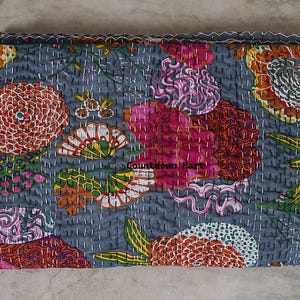 May include: A folded, floral-patterned quilt in shades of gray, pink, orange, and green. The quilt features large, stylized flower designs and is stitched with white thread. The text "Countdown Mart" is visible on the quilt.