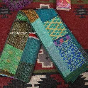 Peut inclure: Textile patchwork aux motifs variés, avec des couleurs vertes, bleues et dorées. Le textile est composé de différents morceaux de tissu cousus ensemble avec des coutures visibles. Le texte "Countdown Mart" est visible sur le textile.