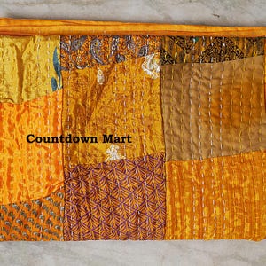 May include: A folded patchwork textile in shades of yellow and orange, with visible stitching. The fabric is composed of various rectangular and square pieces. The text "Countdown Mart" is visible on the textile.