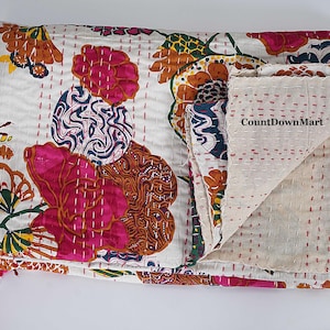 May include: A white, floral-patterned quilt with pink, orange, and blue designs. The quilt features a stitched pattern and the text "CountDownMart". The folded corner reveals a plain, off-white underside.