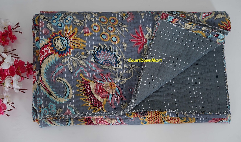 Peut inclure: Une courtepointe grise pli&eacute;e avec des broderies florales color&eacute;es. La courtepointe pr&eacute;sente un motif d&eacute;taill&eacute; de fleurs dans des tons de rouge, de bleu, de jaune et de vert. Le texte "CountDownMart" est visible.