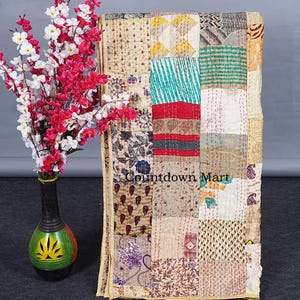 Peut inclure: Une courtepointe patchwork avec une variété de carrés à motifs beiges, rouges, turquoise et floraux. La courtepointe est présentée à côté d'un vase avec des fleurs roses et blanches. Le texte "Countdown Mart" est visible sur la courtepointe.