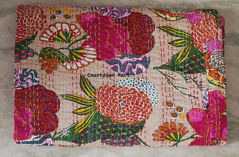 May include: A beige floral quilt with a vibrant design. The quilt features large, stylized flowers in shades of pink, orange, and green, with intricate stitching. The text "Countdown Mart" is visible.