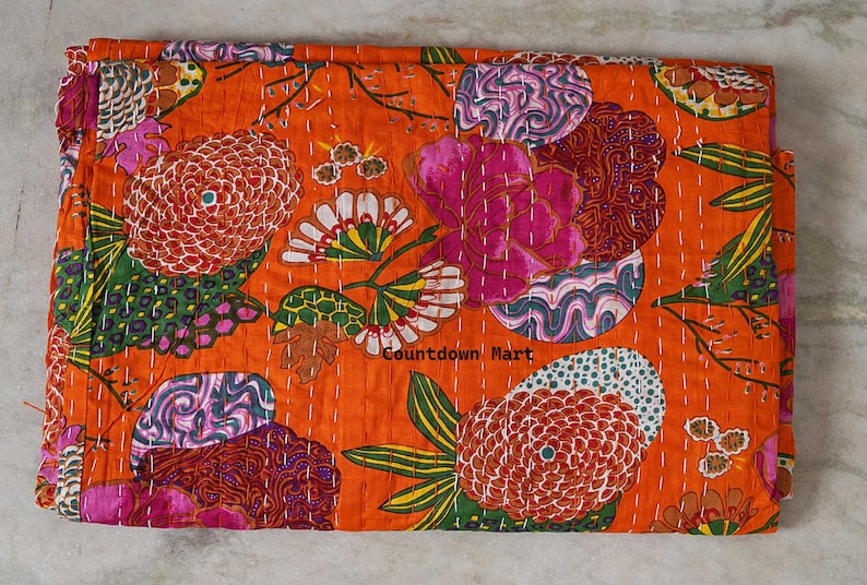 May include: An orange floral patterned quilt with large flowers in shades of pink, white, and red. The quilt has a stitched design and the text "Countdown Mart".