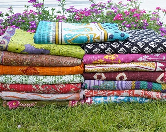 May include: A stack of colorful kantha quilts with various patterns and designs. The quilts are made of recycled saris and are perfect for adding a touch of bohemian style to any room.