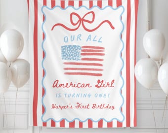 May include: A white banner with red and blue accents, featuring an American flag design and the text "OUR ALL AMERICAN GIRL IS TURNING ONE! Harper's First Birthday." White balloons are arranged around the banner.