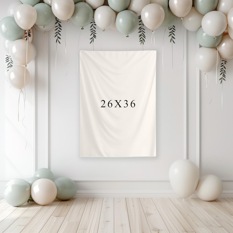 May include: A cream-colored backdrop with the text "26X36" is the focal point, surrounded by a balloon arch in white and sage green. The balloons are arranged with decorative greenery, creating a festive atmosphere. The backdrop measures 26 inches by 36 inches.