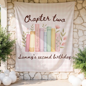 May include: A light pink and white checkered backdrop with the text "Chapter two" and "Sammy's second birthday" in brown script. The backdrop features a watercolor illustration of colorful books and floral accents.