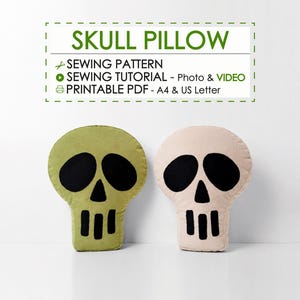 May include: A sewing pattern for a skull pillow, including a tutorial and printable PDF for A4 and US Letter sizes. The image displays two skull-shaped pillows, one in olive green and one in light beige, both featuring black eye and mouth details.