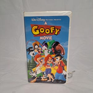May include: A VHS tape for the Disney animated film "A Goofy Movie." The tape has a blue background with the film's title in yellow and red. The cover features cartoon characters Goofy, Max, and other characters in front of a yellow car.