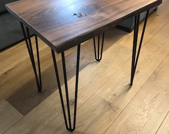 May include: A dark brown wooden table with a live edge top and black hairpin legs. The table is sitting on a light wood floor.