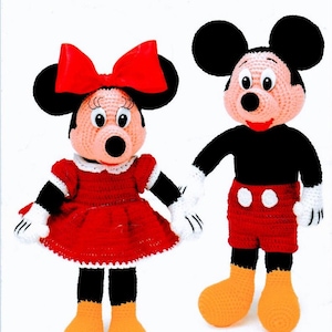 May include: Crocheted Mickey Mouse and Minnie Mouse dolls. Mickey wears red shorts with white buttons, a black shirt, and yellow shoes. Minnie wears a red dress with a white collar and a large red bow. Both have black ears and white gloves.