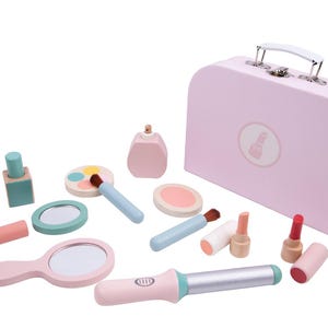 May include: A pink wooden toy makeup set with a matching suitcase. The set includes a mirror, lipstick, nail polish, eye shadow, perfume, and a curling iron. The suitcase has a white handle and silver clasps.