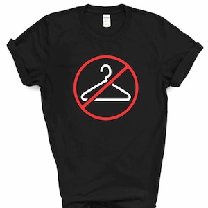 Puede incluir: Camiseta negra con un círculo rojo y un contorno blanco de una percha con una línea que la atraviesa.