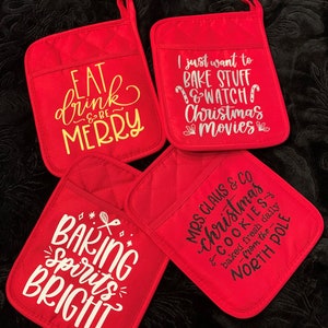 May include: Four red quilted pot holders with different Christmas-themed sayings. The sayings are "Eat, drink & be merry", "I just want to bake stuff & watch Christmas movies", "Baking spirits bright", and "Mrs. Claus & Co. Christmas & Cookies baked fresh daily from the North Pole".