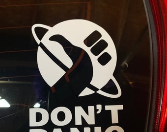 May include: A white sticker on a car window with a black silhouette of a hand giving a thumbs up inside a circle with a ring around it. The text "DON'T PANIC" is below the circle.