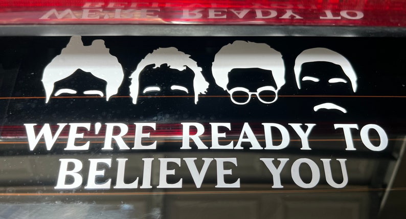 May include: A white vinyl sticker with four cartoon faces and the text "We're ready to believe you".
