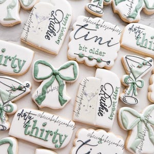 Puede incluir: Una colección de galletas de azúcar decoradas con glaseado verde y blanco. Las galletas presentan varios diseños, incluyendo una copa de martini, un lazo y el texto "dirty thirty" y "tini bit older".