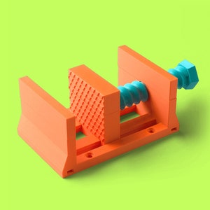 May include: A bright orange plastic clamp with a blue screw. The clamp is made of 3D printed plastic and has a textured surface.