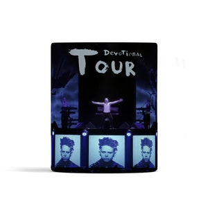 May include: A black and white image of a concert stage with the text "Devotional Tour" in white. A person is standing on stage with their arms outstretched. There are three screens below the stage showing a close-up of a person's face.