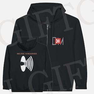 Puede incluir: Sudadera con capucha negra con cremallera y logotipo blanco y naranja en la parte delantera y trasera. El logotipo frontal presenta las letras "DM" dentro de un rectángulo rojo. La parte trasera de la sudadera tiene el texto "MUSIC for MASSES" encima de un gráfico de altavoz blanco.