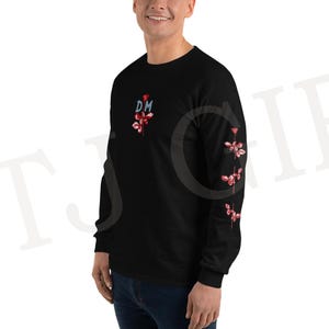 May include: Black long-sleeved shirt featuring a floral design and the letters "DM" in blue and red. The floral design is repeated on the left sleeve. The shirt is made of a soft material.