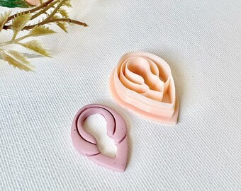 Könnte beinhalten: Zwei rosa Plastik-Blütenblattschneider. Der größere Schneiderschneider hat drei Schichten und der kleinere Schneiderschneider hat eine Schicht.