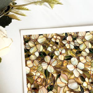 Op de afbeelding: Een close-up van een bloemenontwerp met witte en crèmekleurige bloemen, groene bladeren en bruine accenten. Het ontwerp doet denken aan glas-in-lood. De afbeelding staat op een witte achtergrond.