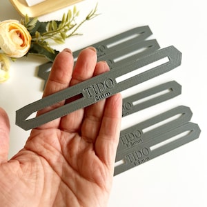 May include: A set of five grey plastic tools for leather crafting. The tools are labelled "TIDO" and have different sizes: 2mm, 3.5mm, and 1.3mm.