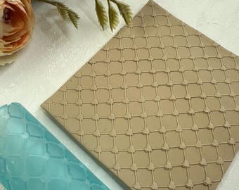 May include: A light blue rolling pin and a brown silicone mat with a repeating geometric pattern. Both tools are used for creating embossed designs on fondant or clay.
