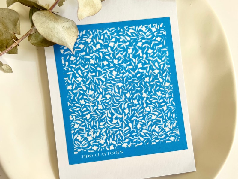 May include: A blue stencil with a white floral pattern. The stencil is labelled "TIDO CLAY TOOLS".