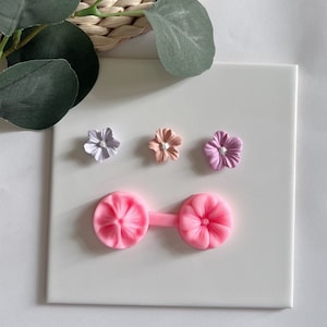 以下が含まれることがあります： パステルカラーのフラワーエンベリッシュメント3個セットと、花の形をしたデコレーションを作るためのピンクのシリコンモールドです。