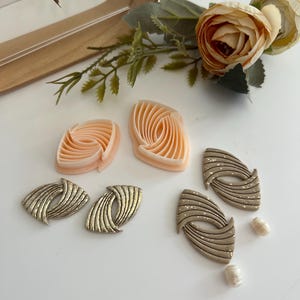 Könnte beinhalten: Ein Set aus drei Keramikbechern mit gesprenkelter, matter Oberfläche. Die Becher sind in Creme-, Hellgrau- und Dunkelgrautönen gehalten. Jeder Becher hat ein schlichtes, minimalistisches Design.